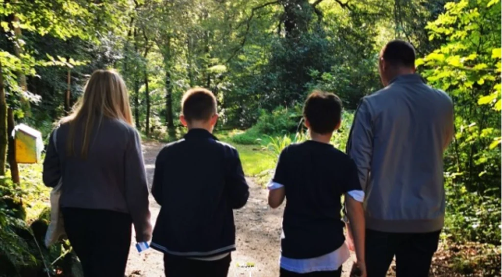 family of four walking away from the camera on a woodland path